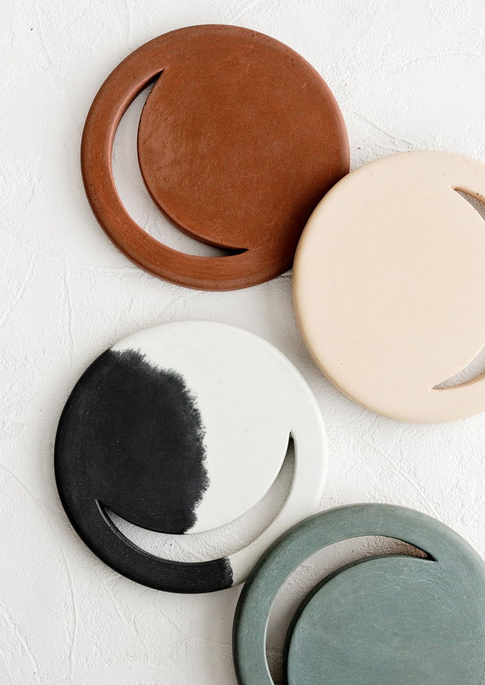 An assortment of round concrete trivets with crescent moon shaped cutout.