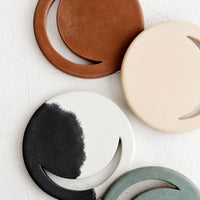 2: An assortment of round concrete trivets with crescent moon shaped cutout.