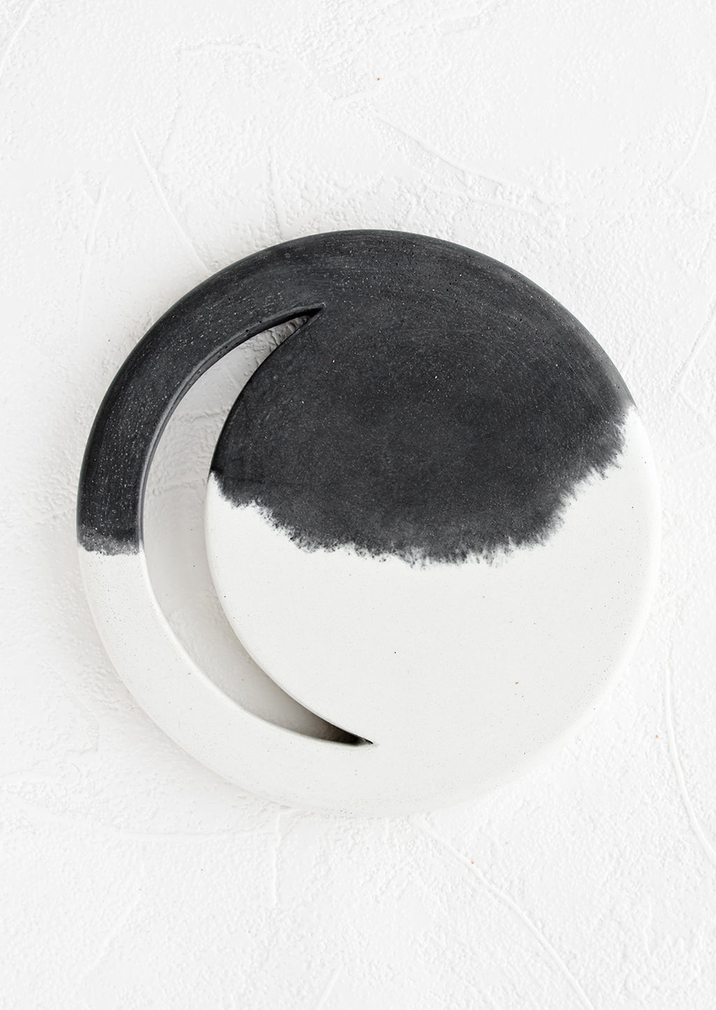 Black & White: A round concrete trivet in black and white with crescent moon shaped cutout.