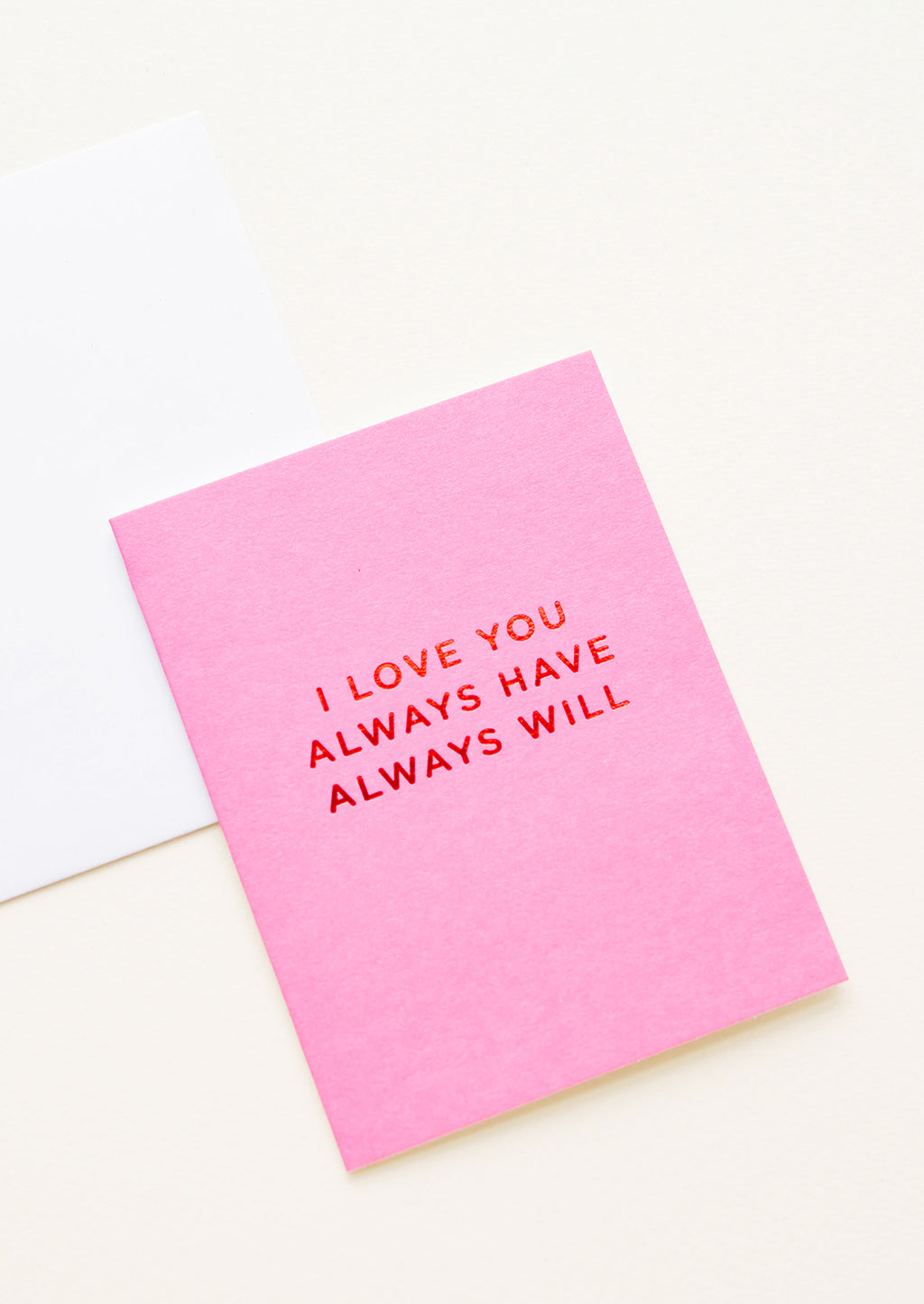 2: A white envelope and bright pink greeting card with the words "I love you always have always will" in red foil.