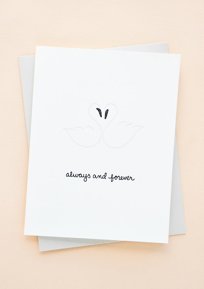Greeting card with letterpress printed swans and "Always and forever" in cursive, with grey envelope.
