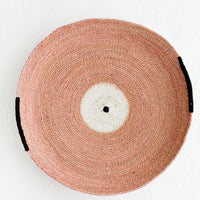 Rose: A round platter/tray made from woven seagrass in pink, white and black.