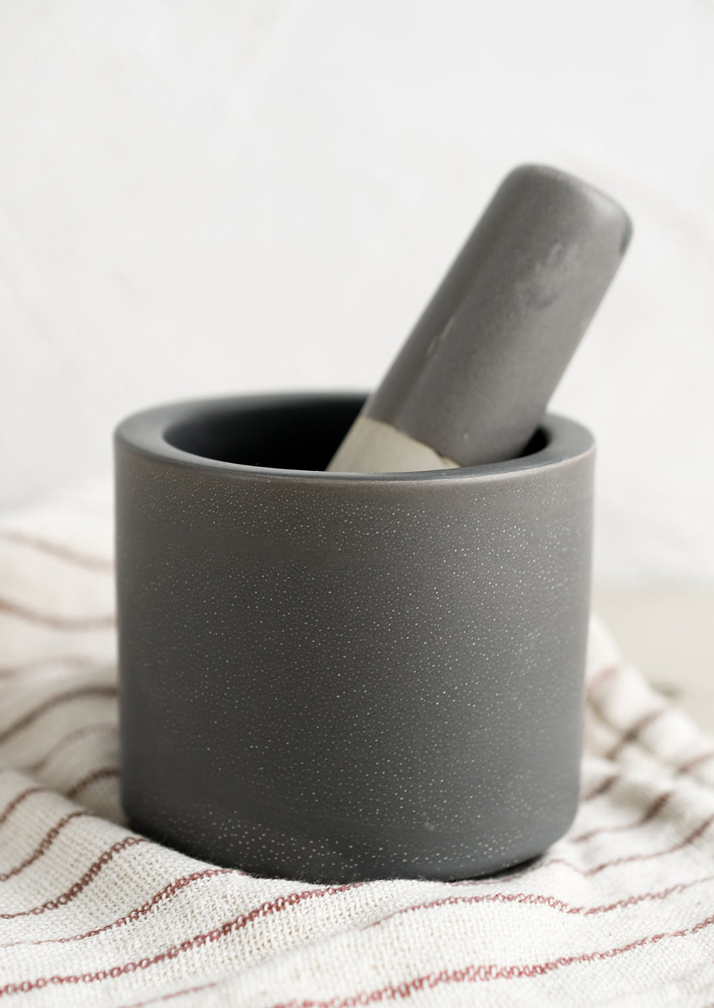 1: A dark grey colored ceramic mortar and pestle set.