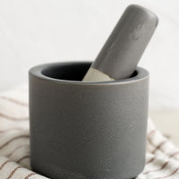 1: A dark grey colored ceramic mortar and pestle set.