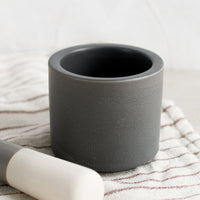 2: A dark grey colored ceramic mortar and pestle set.
