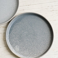 2: A round grey ceramic side plate with light speckles.