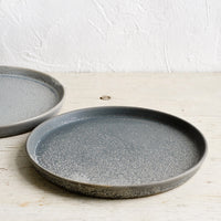 3: Grey side plates on a wooden table.