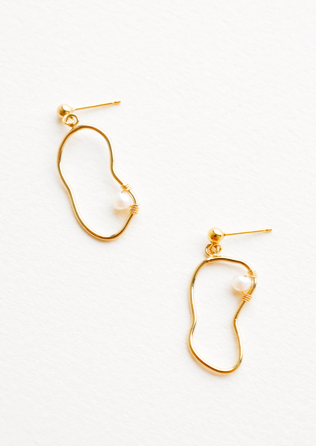 1: Dangling earrings featuring asymmetric round gold charm made from a slim gold hoop, with one pearl attached with wrapped wire.