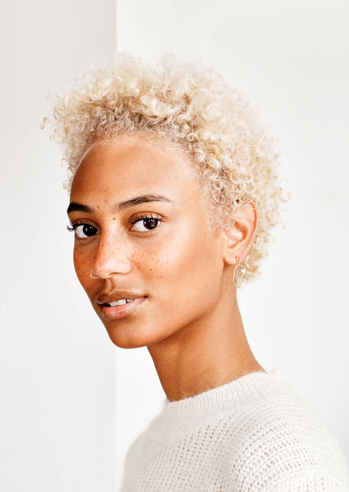 Model shot showing woman wearing earrings and white top.