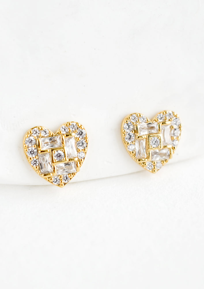 A pair of gold heart shaped stud earrings with a mix of rectangular and round crystal pave detailing.