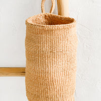 Natural: An oblong cylindrical basket woven from sisal in natural color.