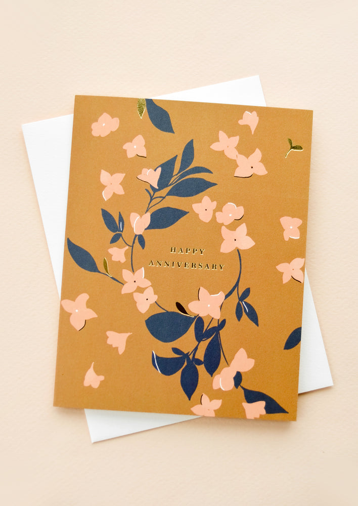 Ochre hued greeting card with scattered floral print and "Happy Anniversary" printed in gold lettering.