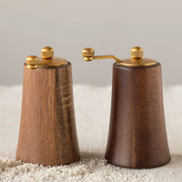1: Wood salt and pepper grinders in light and dark wood tones with brass hardware.