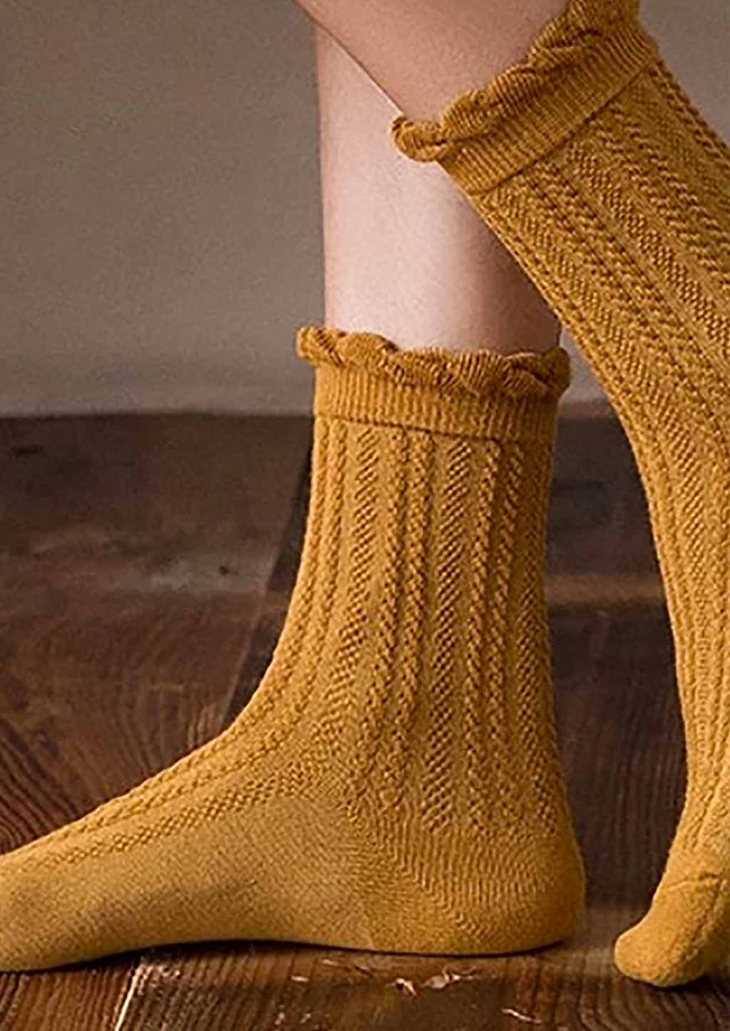 4: A pair of feet wearing cable knit socks that hit above the ankle.