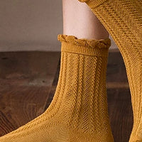 4: A pair of feet wearing cable knit socks that hit above the ankle.