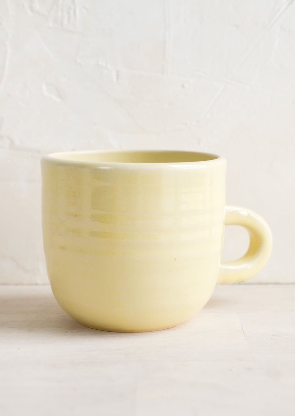 Butter (Glossy): A short ceramic coffee mug in glossy pale yellow glaze.