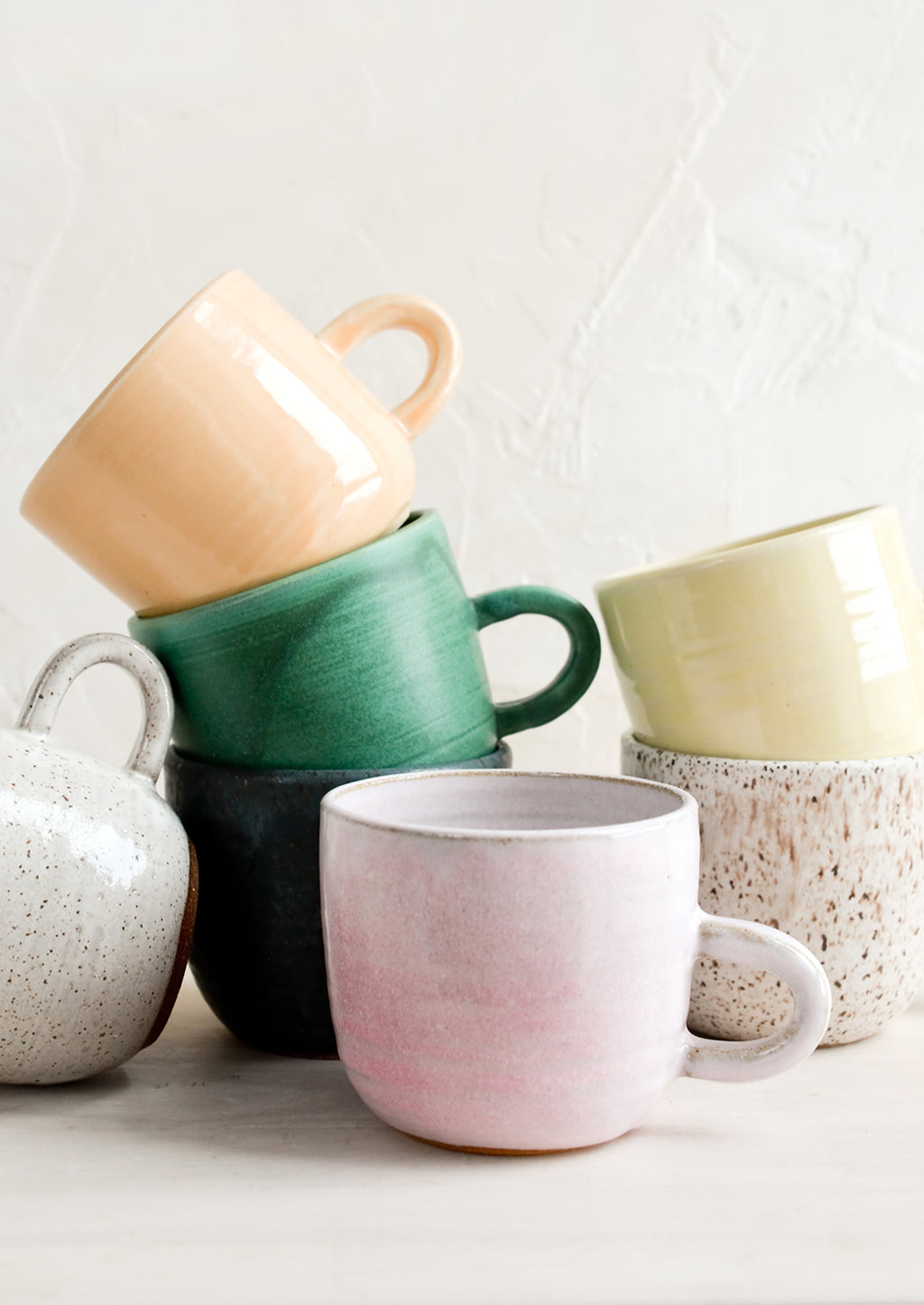 1: A stack of ceramic mugs in a mix of glazes and colors.