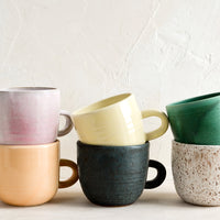 2: A stack of ceramic mugs in a mix of glazes and colors.