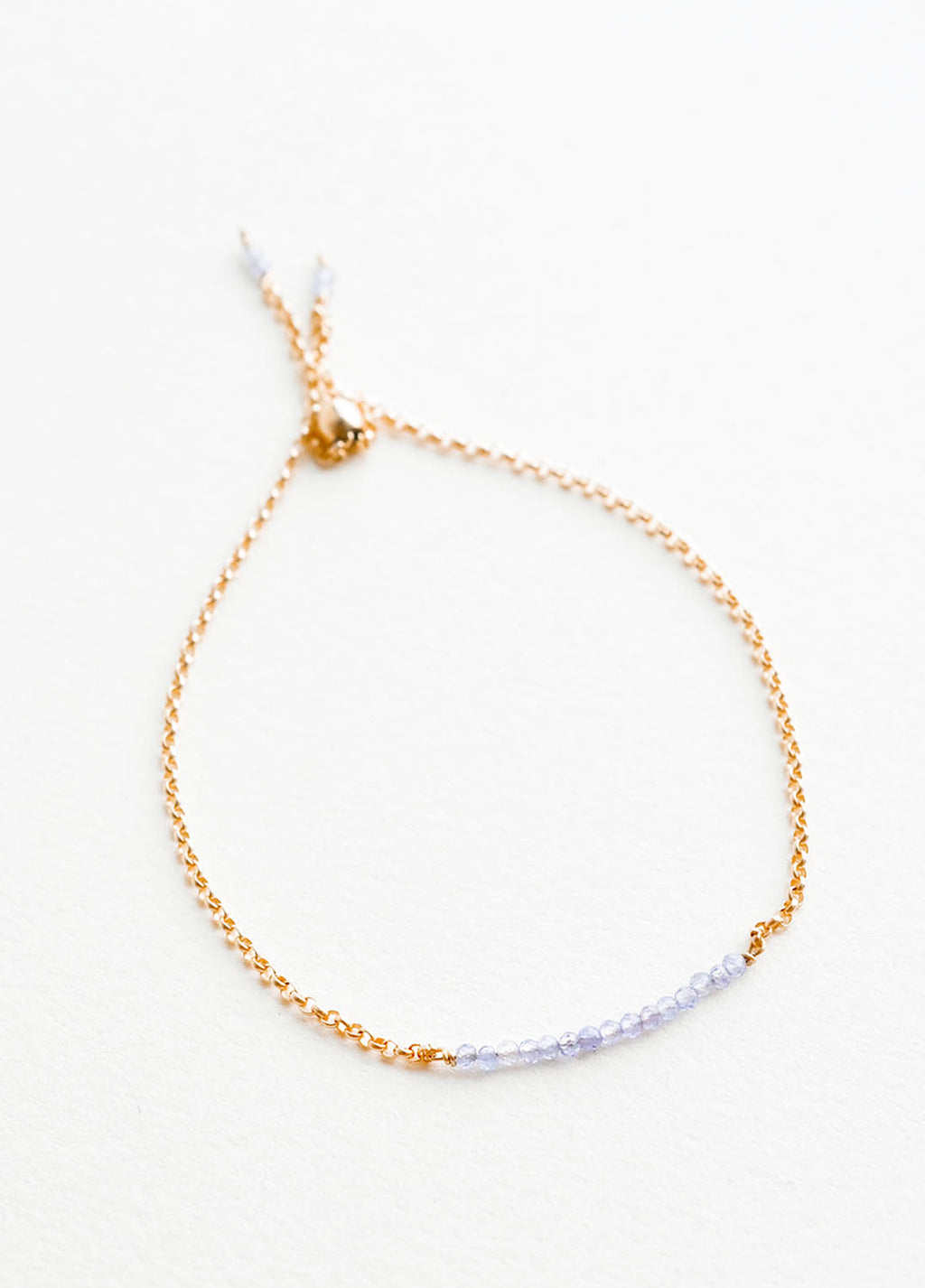 Tanzanite: A delicate gold chain bracelet featuring a row of miniature light blue gemstones.