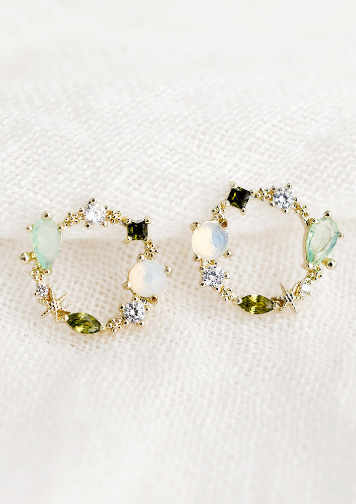 A pair of circle shaped stud earrings with green and clear crystal border.