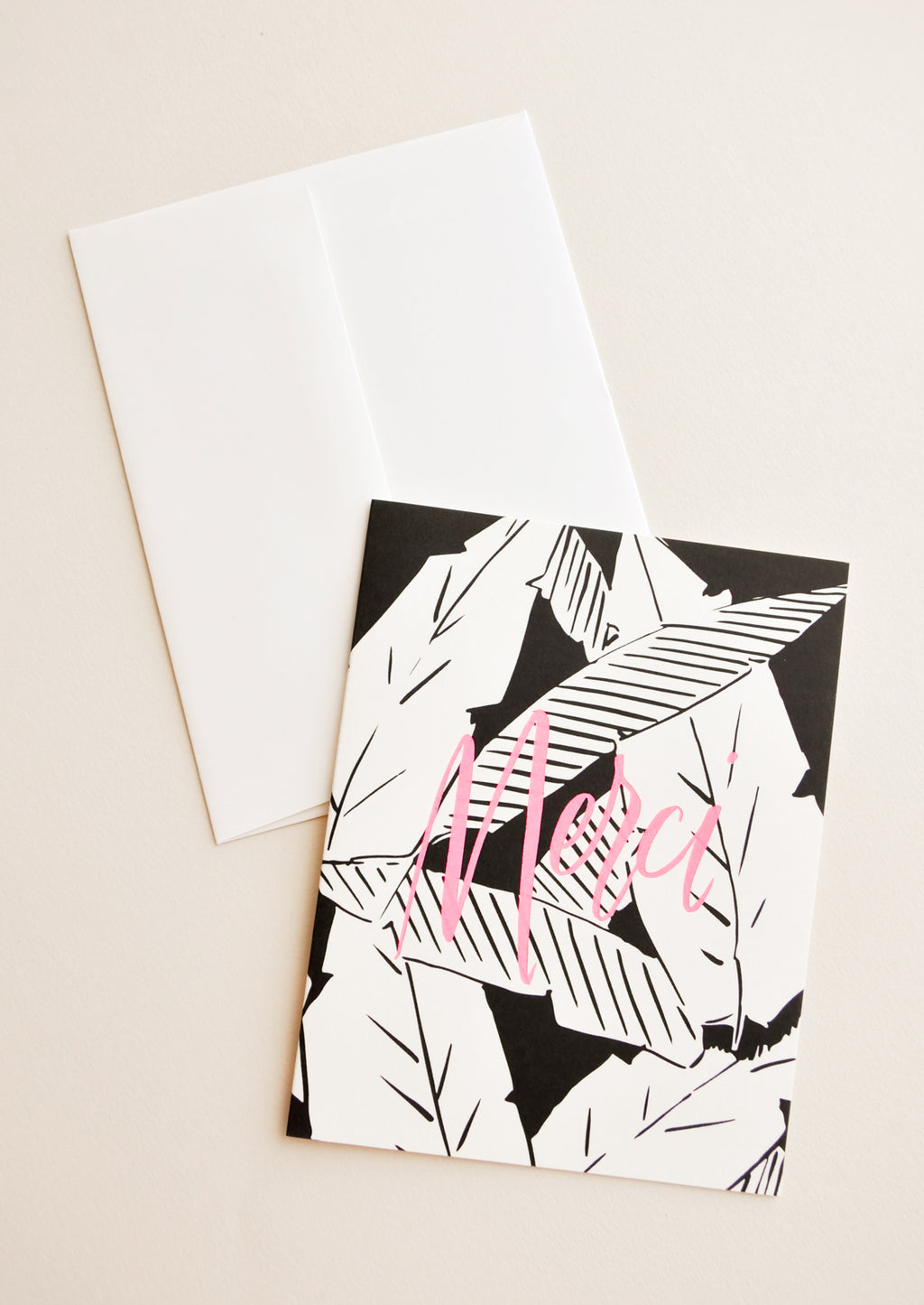 1: Notecard with black and white palm leaves decoration and the word "Merci" in pink, and white envelope.