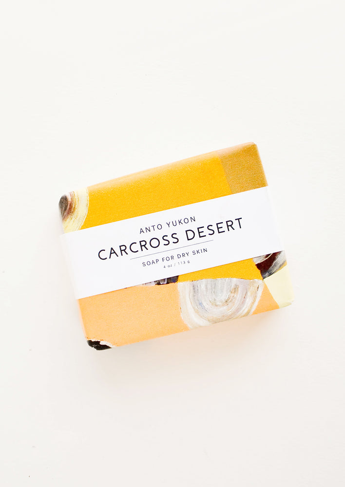 Carcross Desert: A bar of soap in patterned orange packaging with a white horizontal label. 