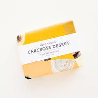 Carcross Desert: A bar of soap in patterned orange packaging with a white horizontal label. 