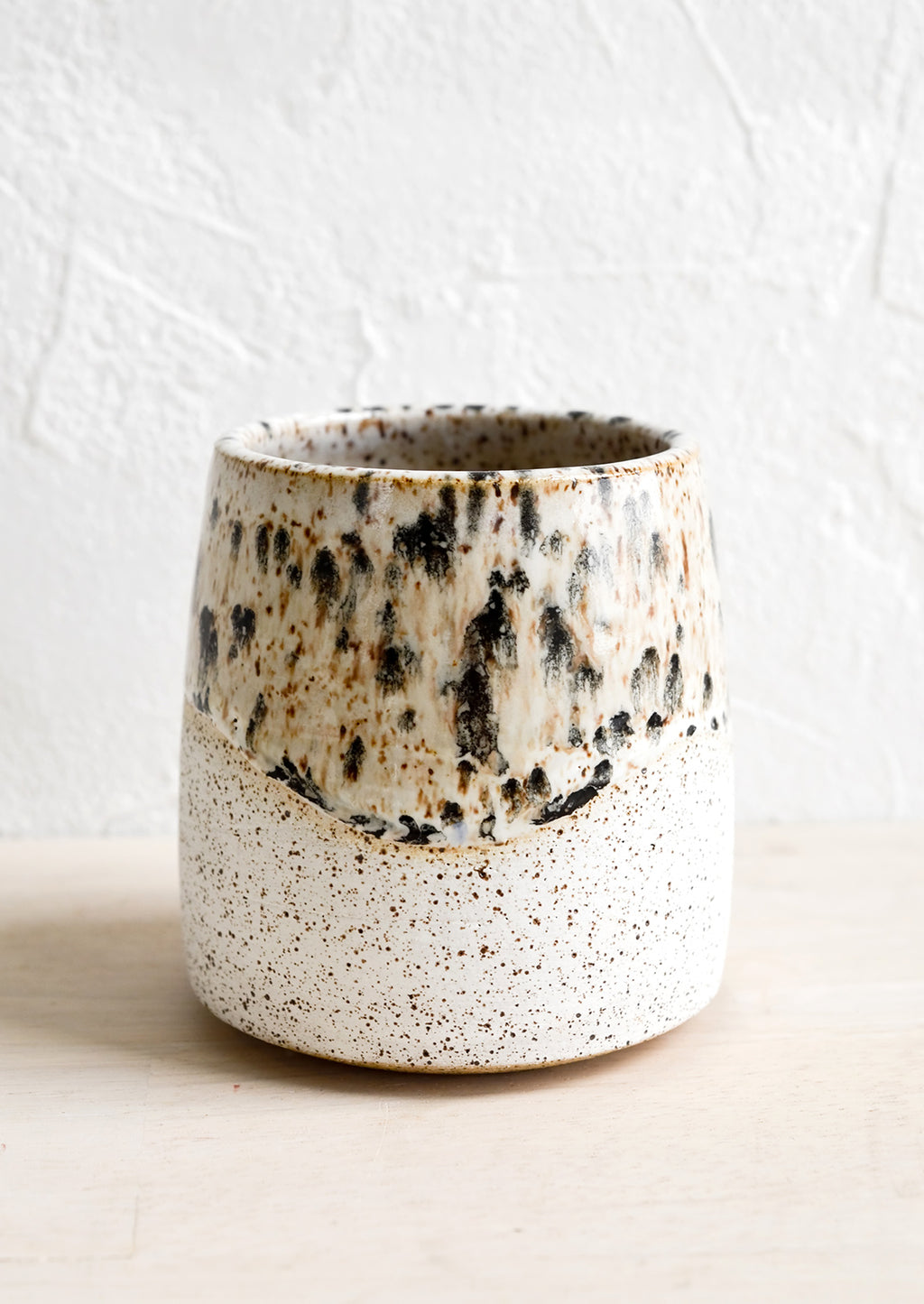 1: White speckled ceramic cup with mottled glaze detail.