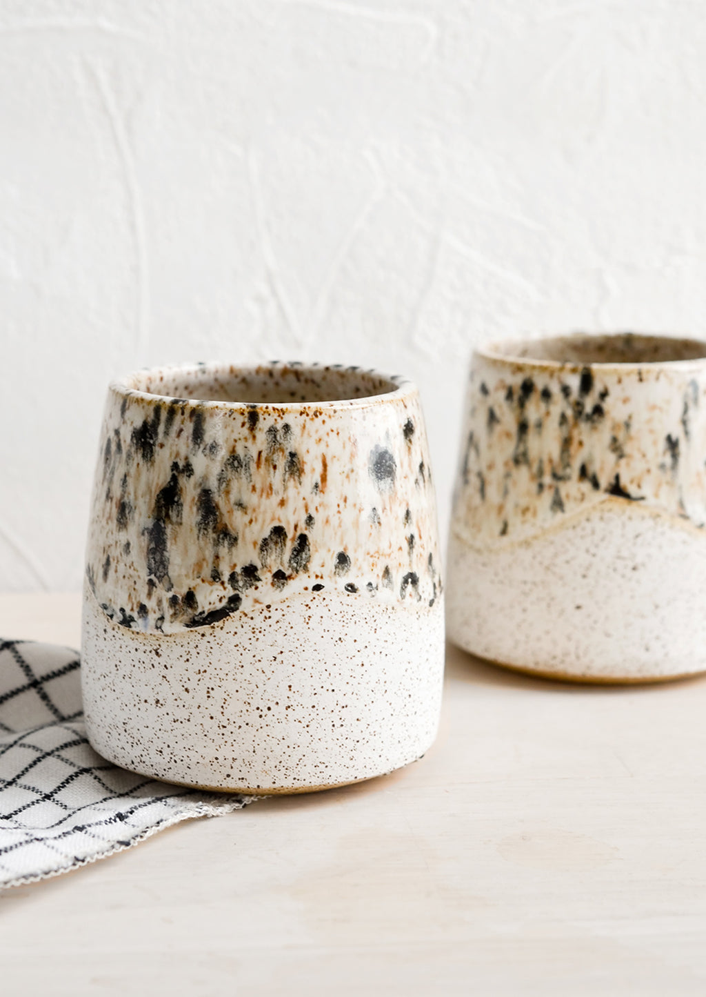 2: White speckled ceramic cups with mottled glaze detail.
