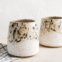 2: White speckled ceramic cups with mottled glaze detail.