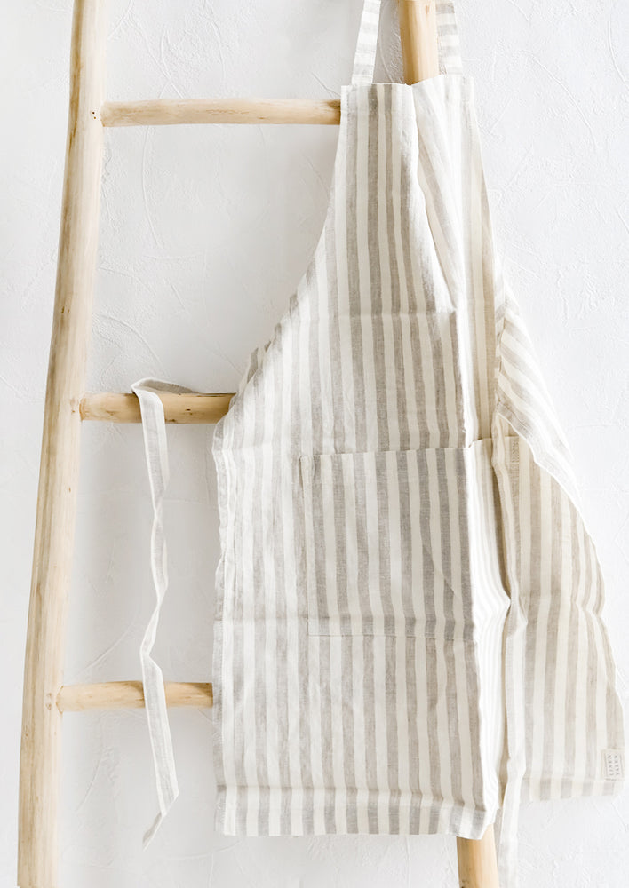 A tan and white striped linen apron hung on a wooden ladder.