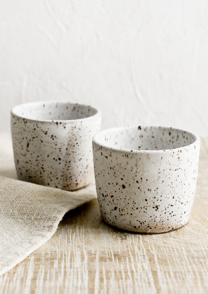 Two espresso cups in speckled white ceramic.