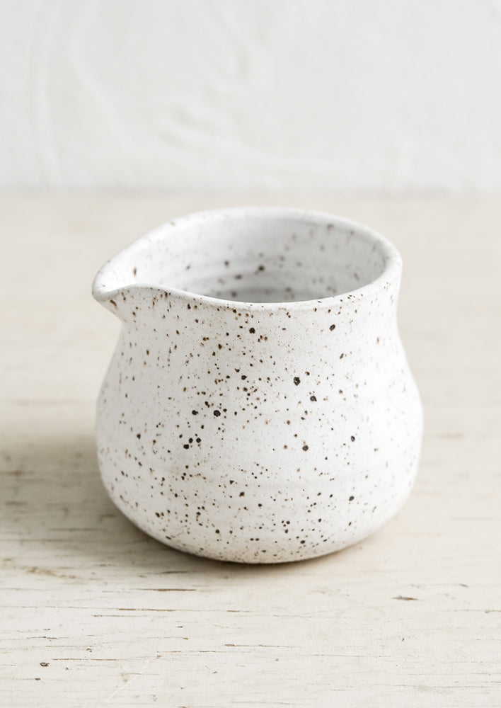 A small white pitcher in speckled ceramic.