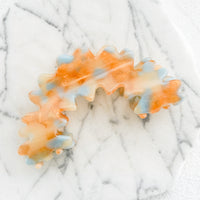 Mandarin: An orange and blue acetate hair claw in squiggly arch shape.