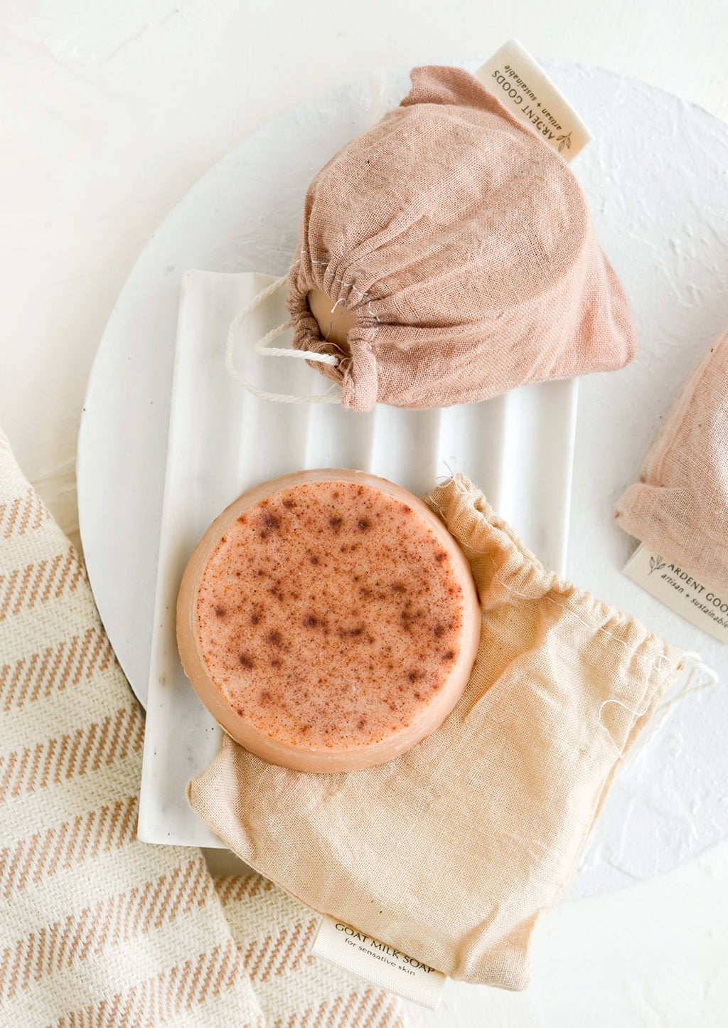 2: A round soap bar with naturally dyed muslin pouches.