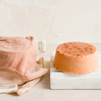 3: A round soap bar with naturally dyed muslin pouches on marble soap dish.