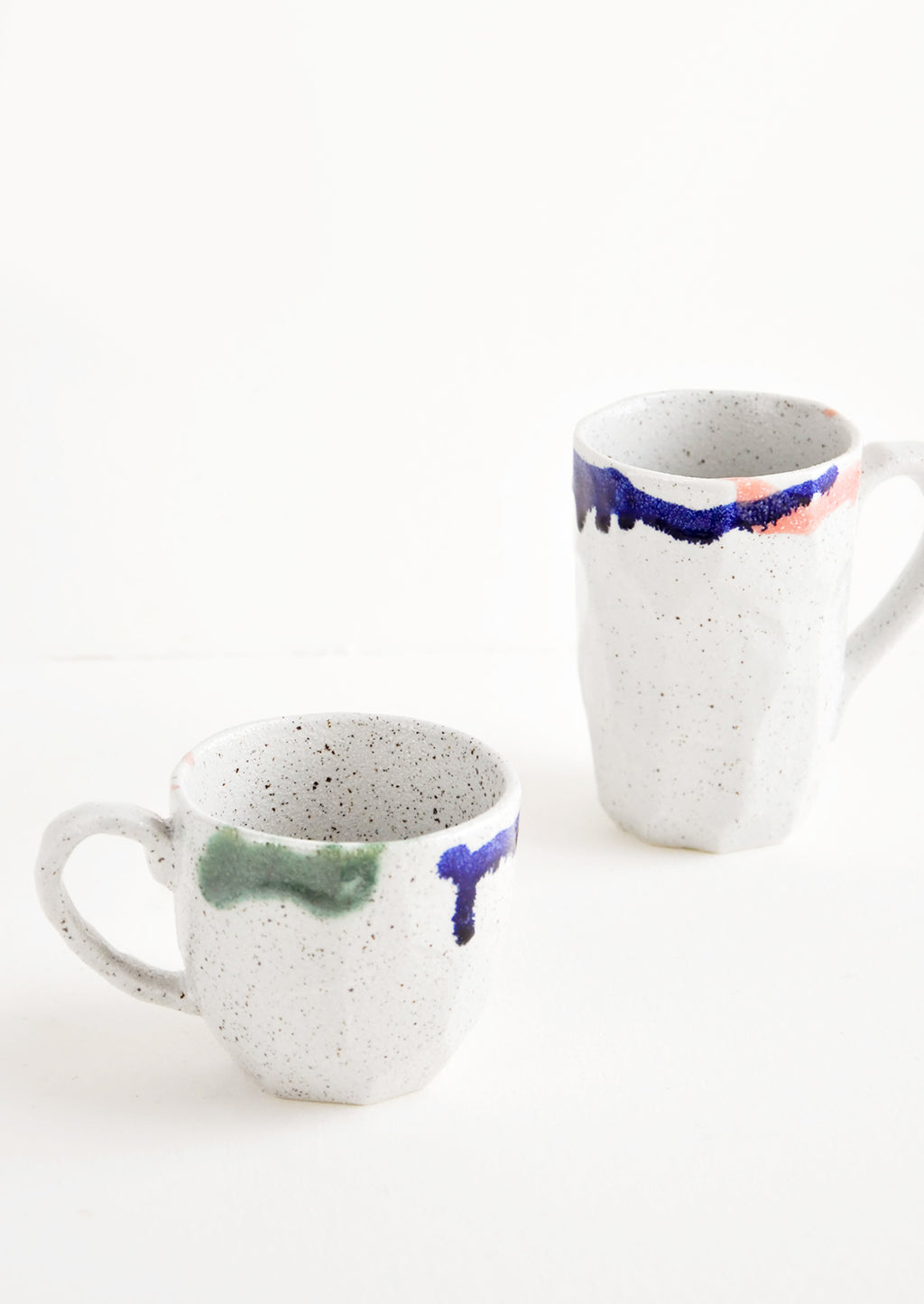 1: Two differently sized gray ceramic mugs with blue, green, and pink painted rims.