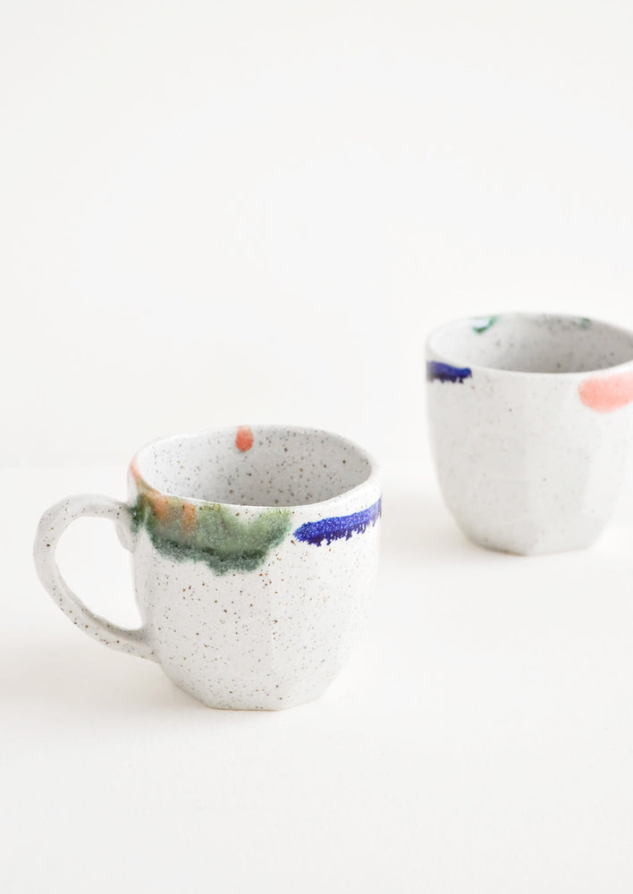 Two short gray ceramic mugs with blue, green, and pink painted rims.