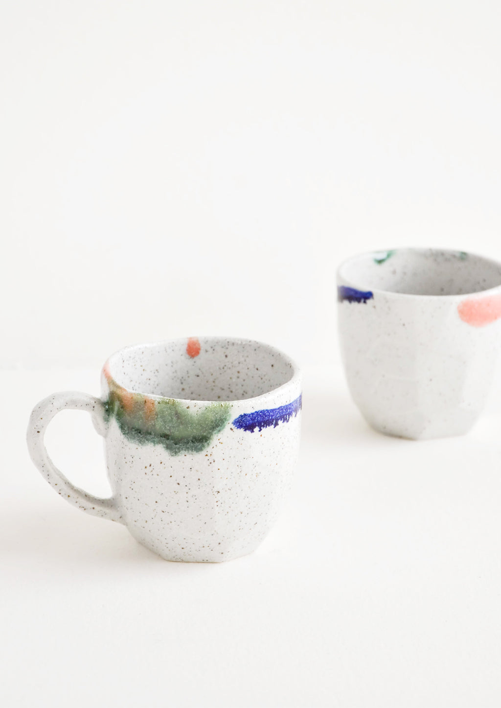 3: Two short gray ceramic mugs with blue, green, and pink painted rims.