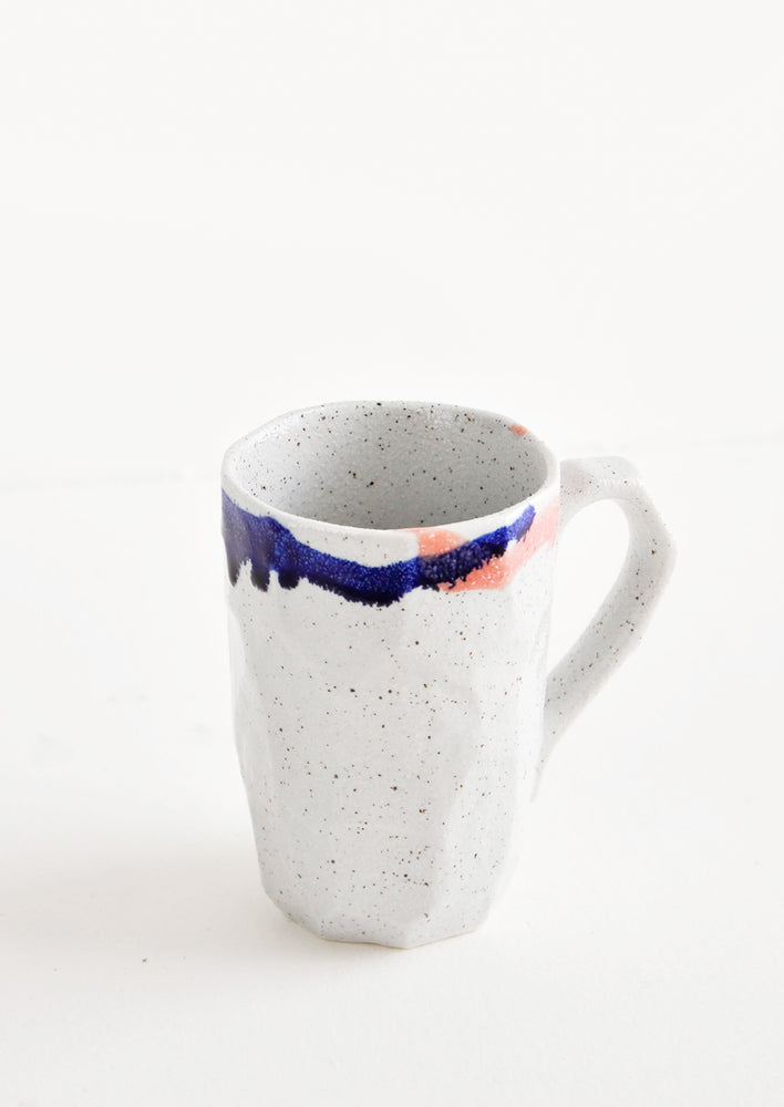 A tall gray ceramic mug with blue, green, and pink painted rims.