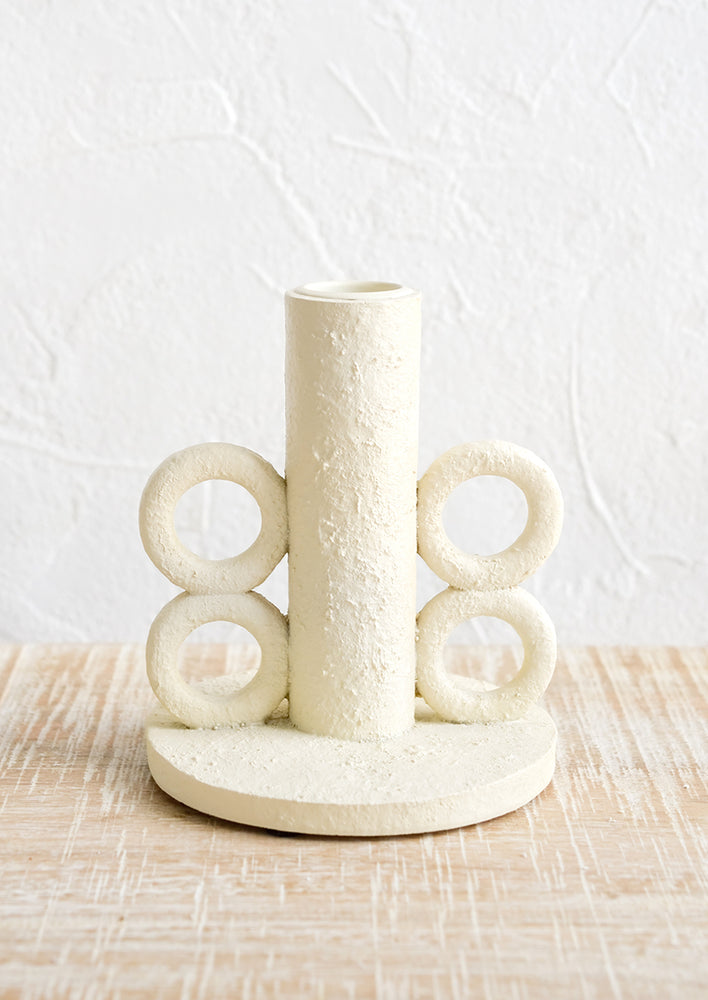 1: A taper candle holder in plaster finish with loop detailing at sides.