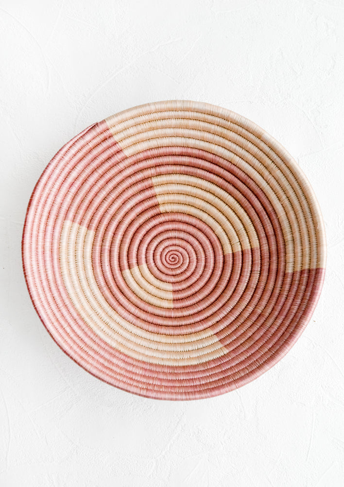 A woven sweetgrass bowl in geometric pink pattern.