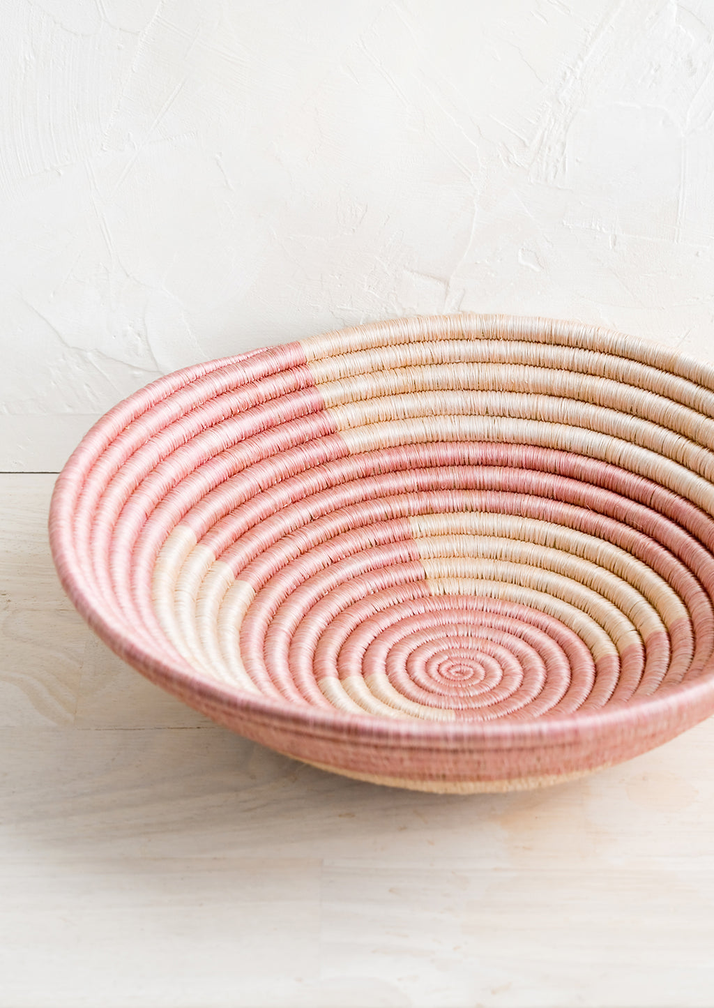 2: A woven sweetgrass bowl in geometric pink pattern.
