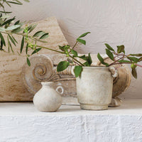 2: A distressed beige ceramic vase with handles at top sides.
