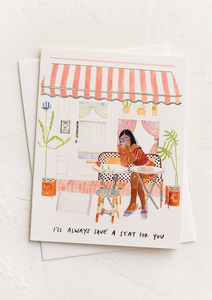 A greeting card with illustration of woman sitting at cafe.