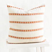 1: Square throw pillow with horizontal rows of geometric embroidered detailing.