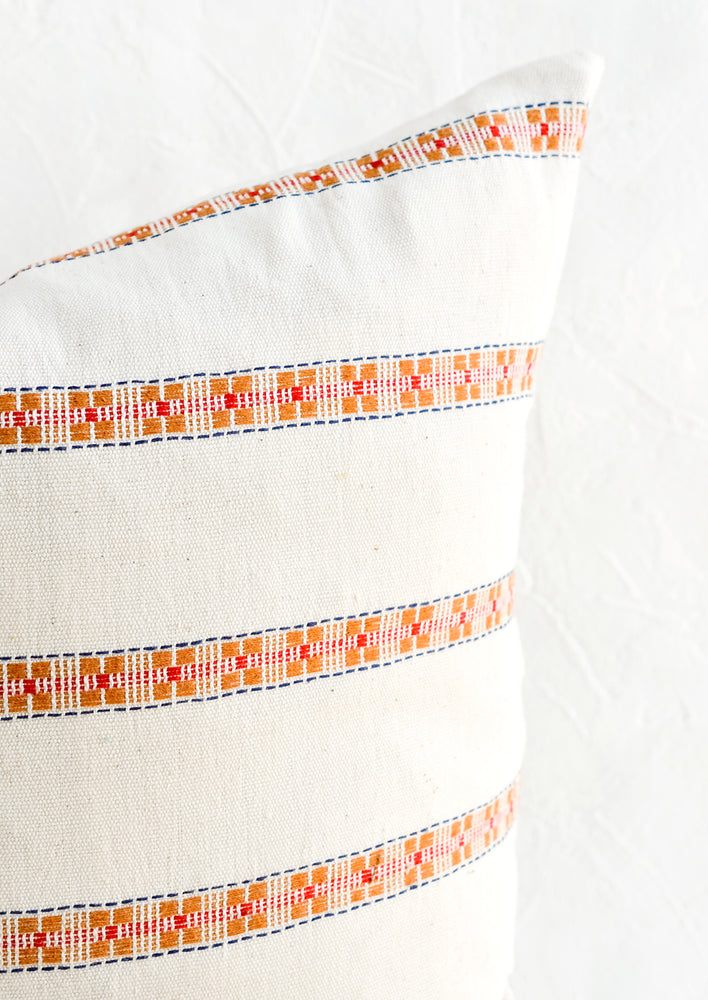 Intricate, geometric embroidery detailing on cotton throw pillow.