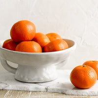 1: A footed ceramic bowl holding oranges.