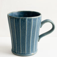 2: A blue ceramic mug with fluted texture and tapered bottom.