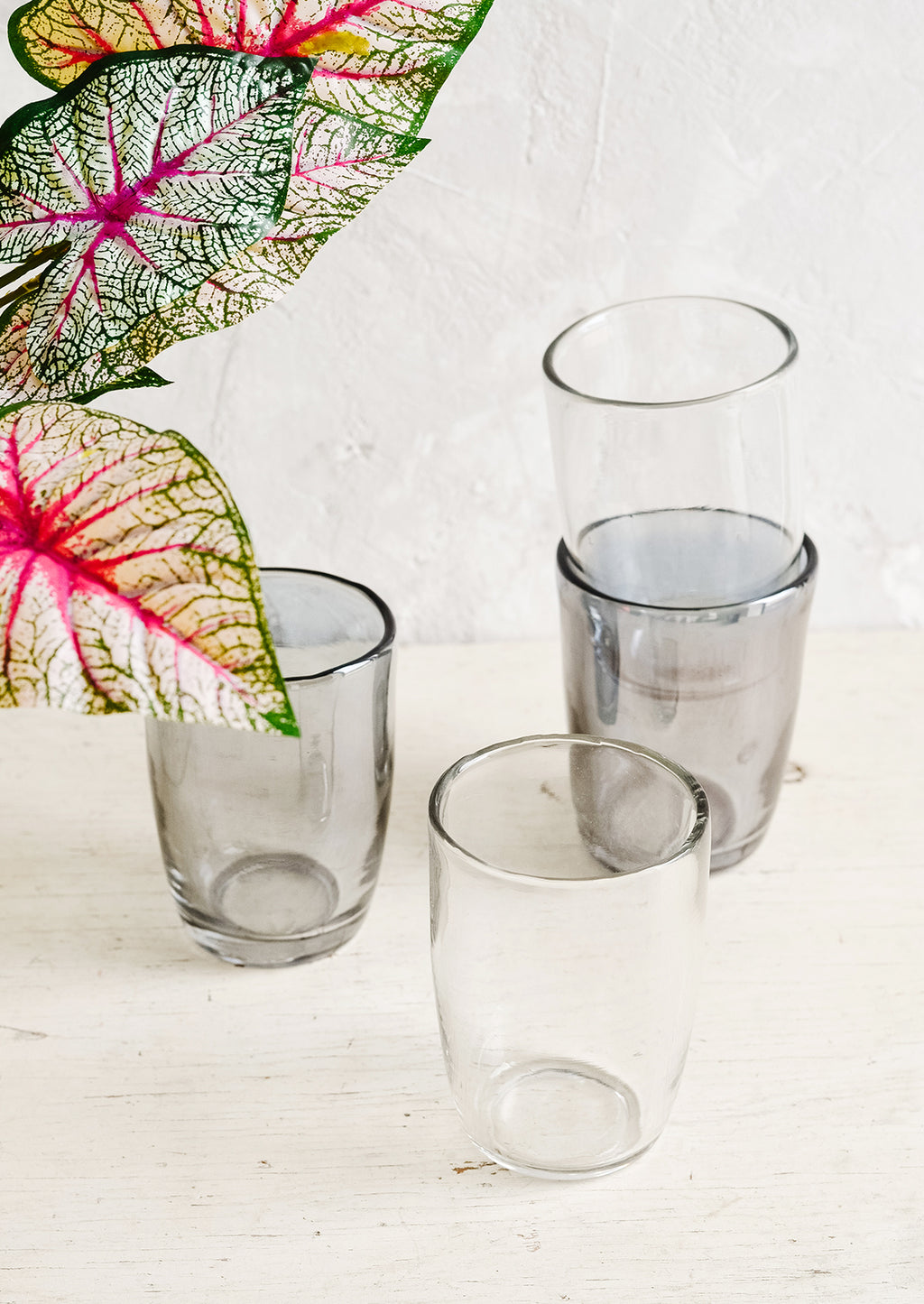 1: Clear and grey glass cups on a table with plant